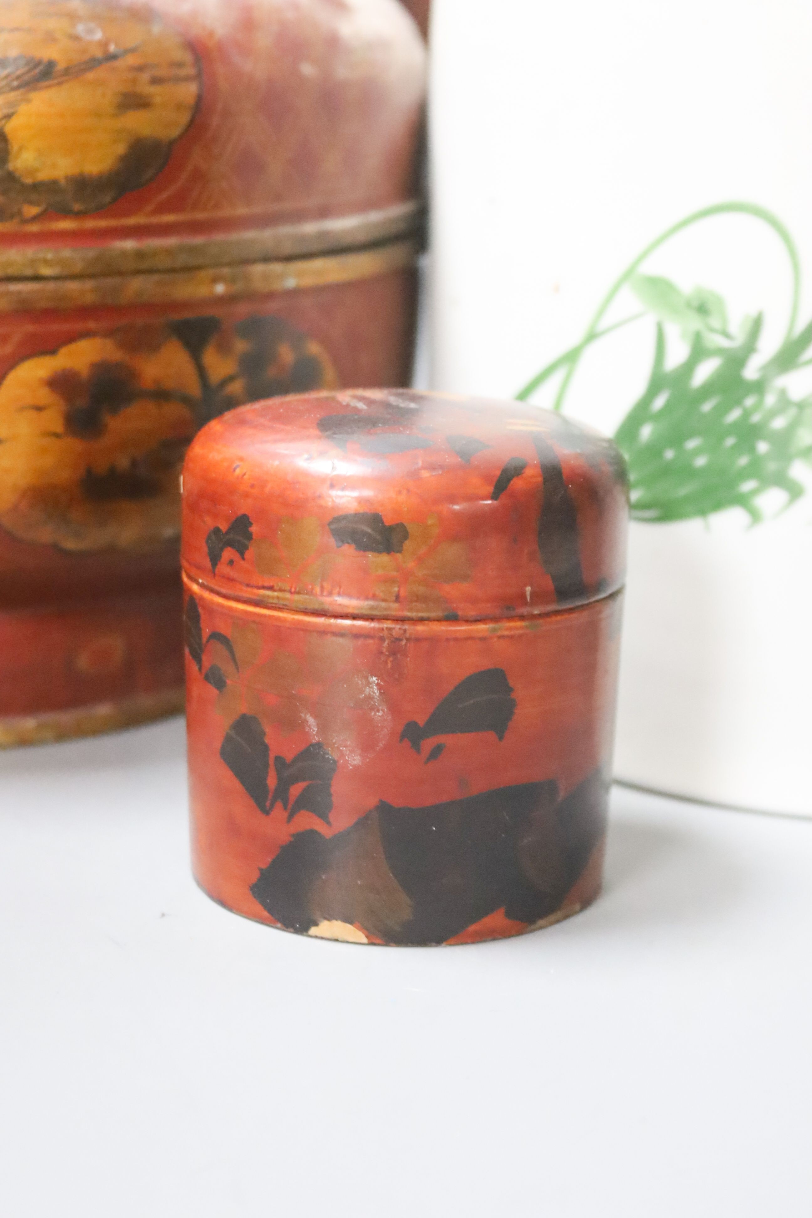 A Chinese large cylindrical porcelain teapot, with bamboo handle and polychrome-decorated with flowers and birds, H 24cm, together with two Japanese red-lacquered containers